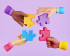 3D animatie van 4 handen die 4 puzzel stukjes vasthouden. De mouwen en puzzelstukjes zijn paars, blauw, rood en geel.