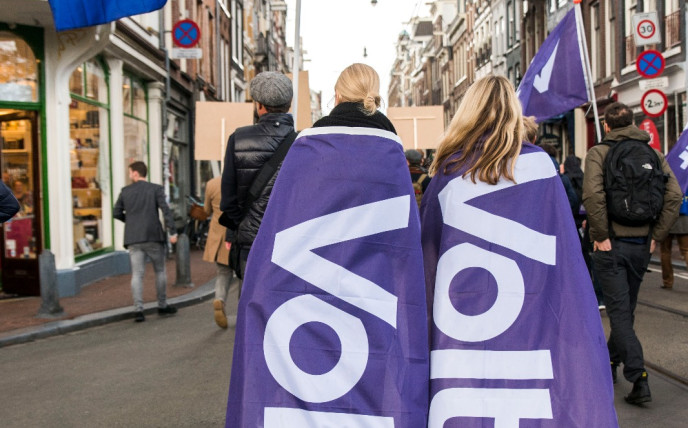 2 mensen lopen met een volt vlag op hun rug