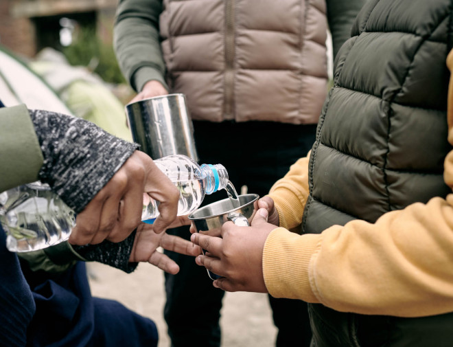 Een persoon die water inschenkt voor een kind