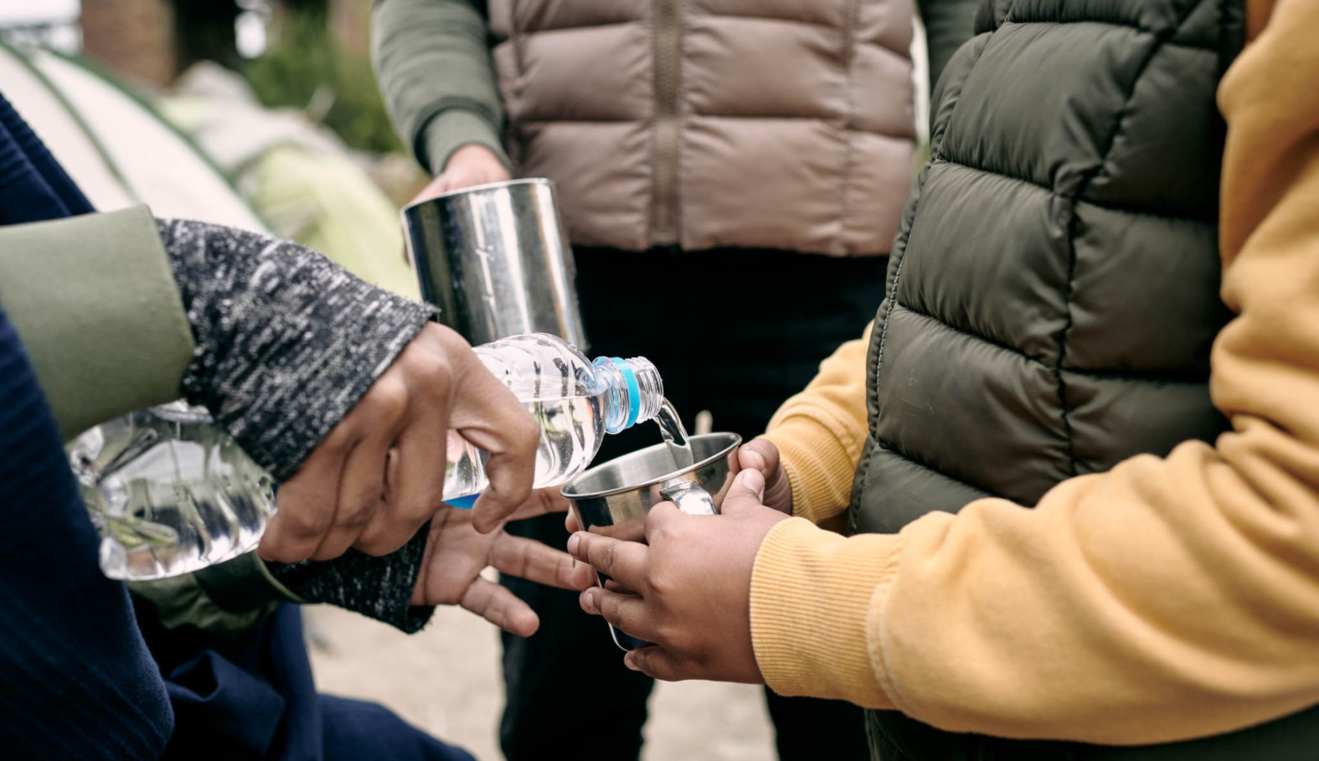 Een persoon die water inschenkt voor een kind