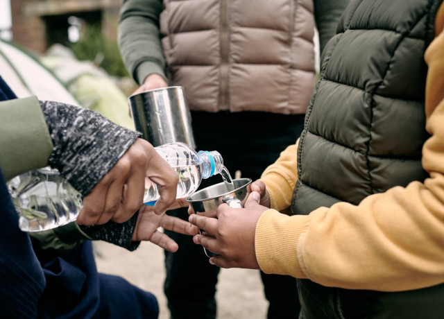 Een persoon die water inschenkt voor een kind