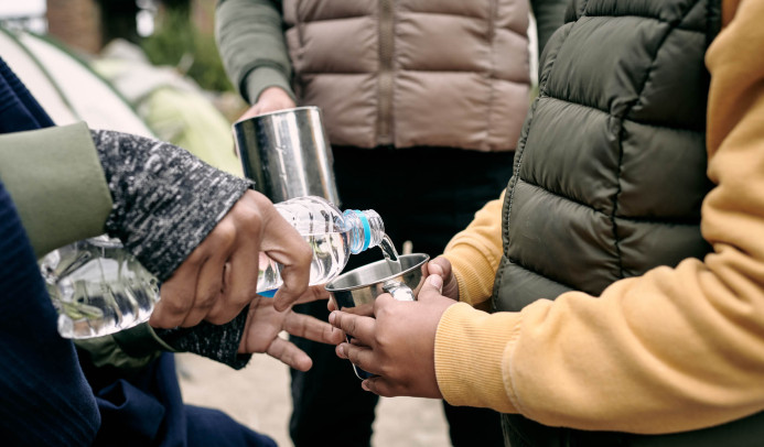 Een persoon die water inschenkt voor een kind