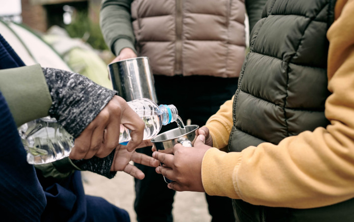 Een persoon die water inschenkt voor een kind