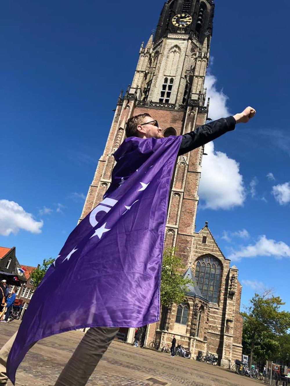 Vrijwilliger draagt volt vlaag als cape en poseert als superheld voor de domtoren