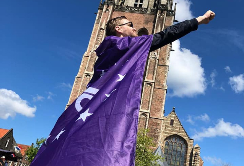 Vrijwilliger draagt volt vlaag als cape en poseert als superheld voor de domtoren