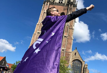 Vrijwilliger draagt volt vlaag als cape en poseert als superheld voor de domtoren