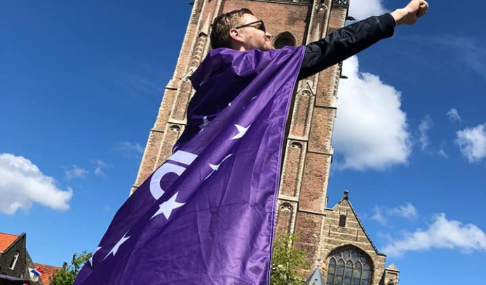 Vrijwilliger draagt volt vlaag als cape en poseert als superheld voor de domtoren