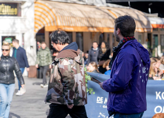 Volter deelt flyers uit op een plein