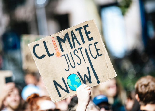 Tijdens protens houd iemand een kortonenbord omhoog met de tekst: Climate justice now