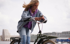 Een tienermeisje op een fiets die op haar telefoon kijkt