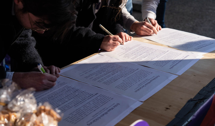 Drie mensen zetten hun handtekening onder een document