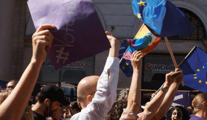 Mensen houden Europese en pride vlaggen omhoog. Ook een papiertje met #Vote Volt