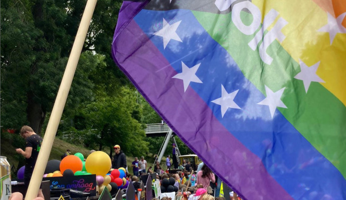 Volters op een pride parade. Ze houden een grote pride volg omhoog met het Volt logo er in.