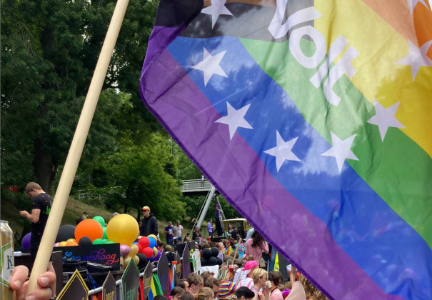 Volters op een pride parade. Ze houden een grote pride volg omhoog met het Volt logo er in.