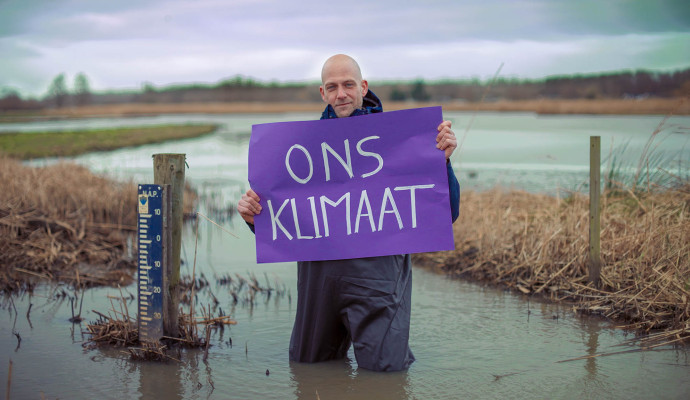 Man in water die paars vel vasthoudt met woorden Ons Klimaat