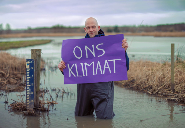 Man in water die paars vel vasthoudt met woorden Ons Klimaat