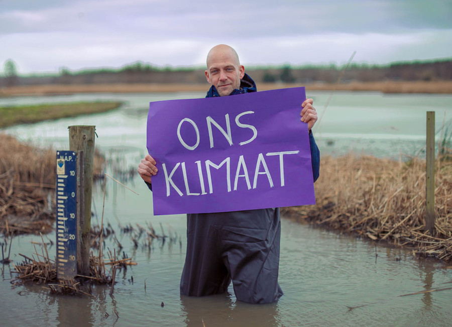 Man in water die paars vel vasthoudt met woorden Ons Klimaat