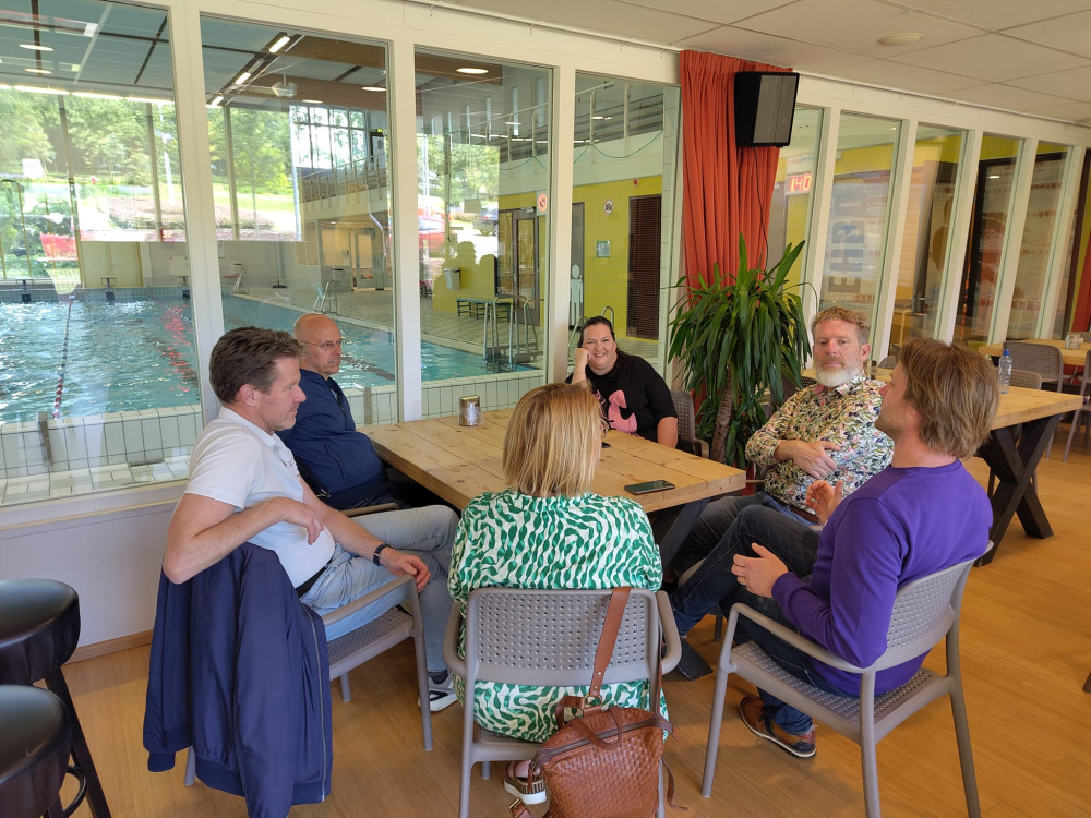 Een groep leden van Volt vergadert aan de tafel van een clubhuis.