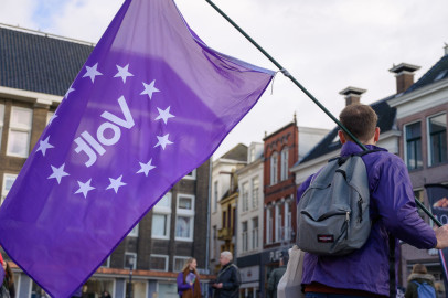 Een Volt-lid van achteren die een paarse Volt vlag vasthoudt