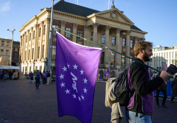 Volter met volt vlag die aan het flyeren is voor het stadhuis in Groningen.
