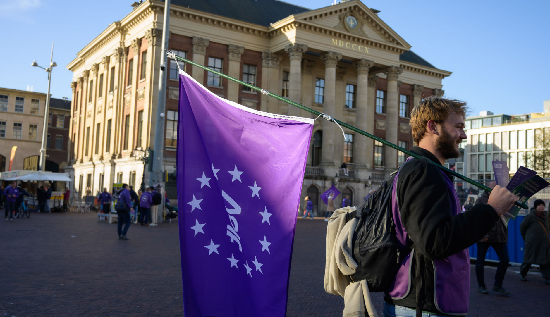 Volter met volt vlag die aan het flyeren is voor het stadhuis in Groningen.
