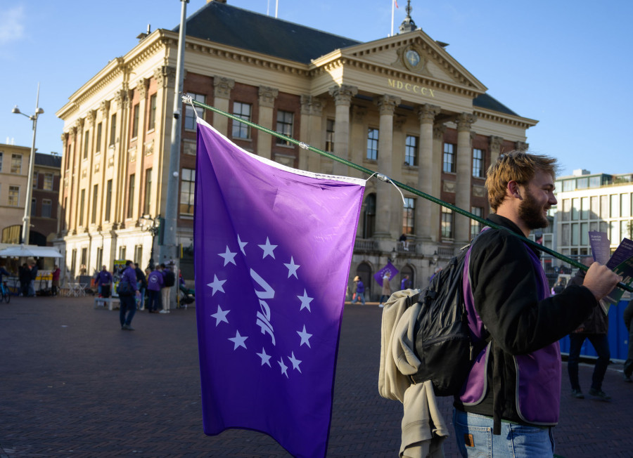 Volter met volt vlag die aan het flyeren is voor het stadhuis in Groningen.