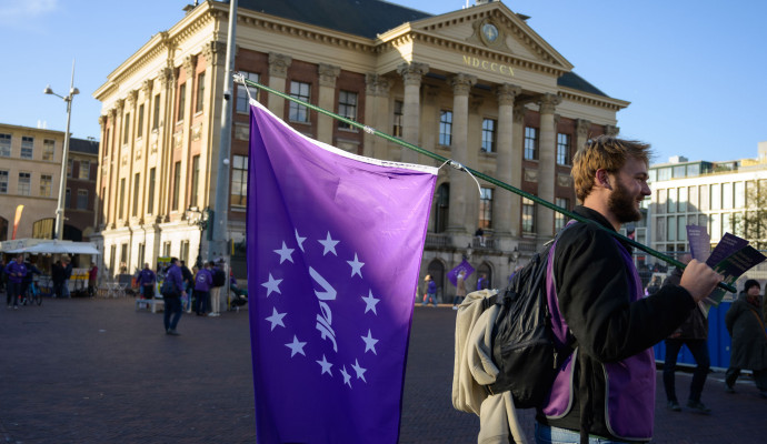 Volter met volt vlag die aan het flyeren is voor het stadhuis in Groningen.