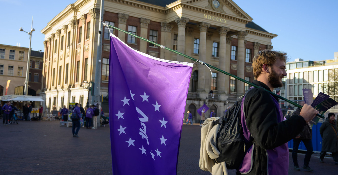 Volter met volt vlag die aan het flyeren is voor het stadhuis in Groningen.