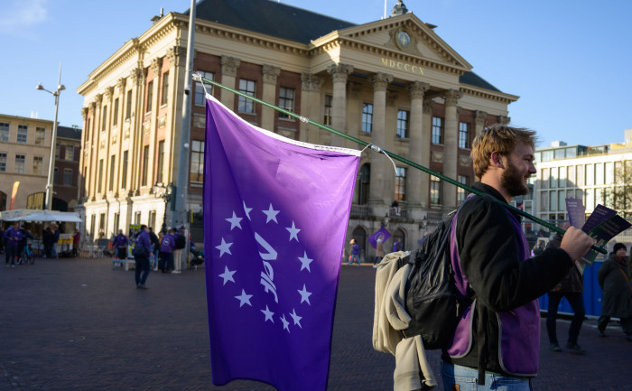Volter met volt vlag die aan het flyeren is voor het stadhuis in Groningen.
