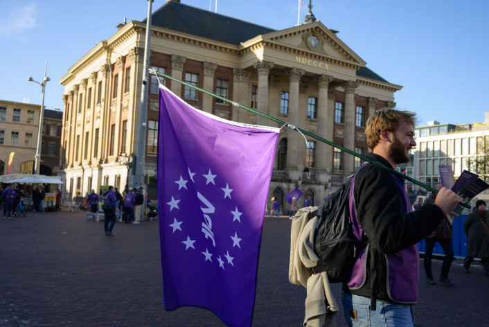 Volter met volt vlag die aan het flyeren is voor het stadhuis in Groningen.