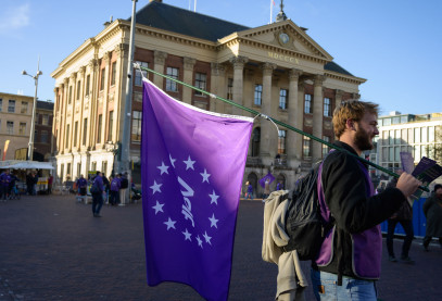 Volter met volt vlag die aan het flyeren is voor het stadhuis in Groningen.