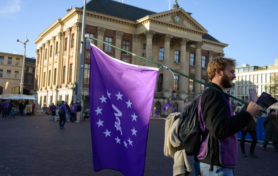 Volter met volt vlag die aan het flyeren is voor het stadhuis in Groningen.
