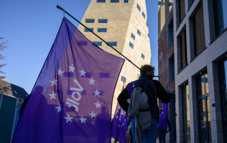 Een Volt-lid die een paarse Volt vlag vasthoudt bij het Forum in Groningen