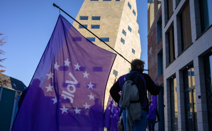 Een Volt-lid die een paarse Volt vlag vasthoudt bij het Forum in Groningen